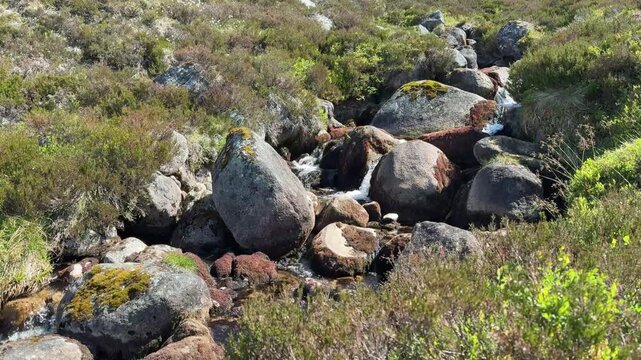 Boulders and fast flowing water in cool, clear mountain stream Cairngorms, Scotland