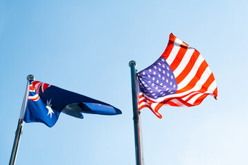 Australian and USA flags flying in the blue sky