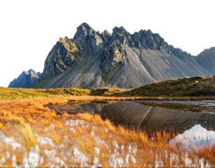 Majestic mountain range reflected in still water, framed by autumn grasses
