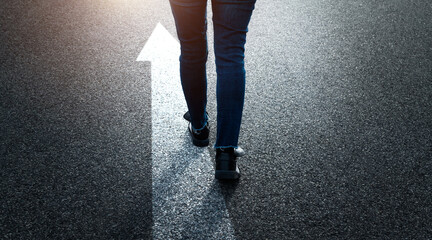 Woman standing on asphalt road with the arrow sign