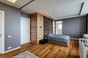 Modern bedroom with wooden floors, gray walls, textured headboard, and soft lighting