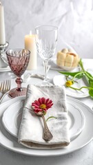Elegant tablescape, featuring plates, glassware, candles, flower, and a wrapped dessert