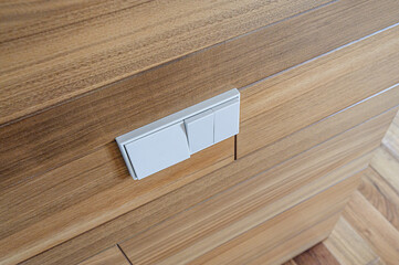 Close-up of a white electrical switch on a wooden surface, showing a modern, clean aesthetic
