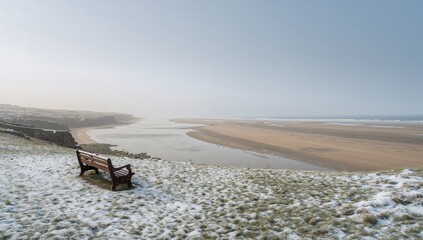 A snowy bench overlooking the shore and river at a well-known coastal spot in Suffolk