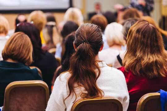 Female audience at the symposyum meeting, participants attendees in conference room hall listens to lecturer, group of women on a medical congress together listen to speaker on a stage at master-class