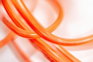 Single orange electrical cable on a white backdrop with clipping path and focused selection.