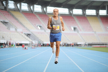 Fototapeta premium Senior man running a marathon in a sports arena