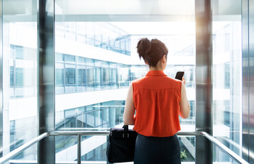 Businesswoman using mobile phone in the elevator
