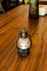 Vintage mini lantern with a flickering LED candle on a rich wooden table, evoking a cozy, rustic, and warm atmosphere