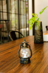 Vintage mini lantern with a flickering LED candle on a rich wooden table, evoking a cozy, rustic, and warm atmosphere