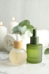 Beautiful spa composition with essential oils and eucalyptus on white marble table, closeup