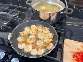 Shrimps and pasta cooking on stove in kitchen, closeup