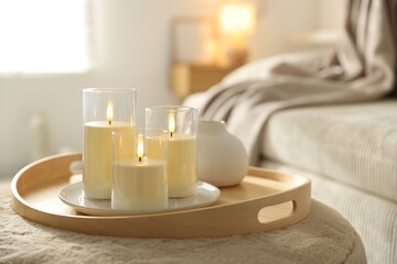Beautiful LED candles and vase on pouf indoors, closeup. Space for text