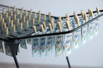 Money laundering. Banknotes hanging on drying rack indoors, closeup