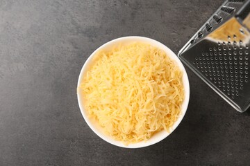 Grated cheese and grater on grey table, top view