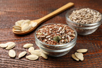 Different seeds in bowls on wooden table, closeup