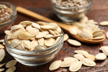 Unpeeled pumpkin seeds on wooden table, closeup
