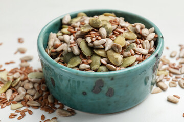 Mix of seeds in bowl on white table, closeup