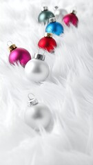 Colorful shiny ornaments, some in focus, are arranged on a soft, fluffy, white textile background