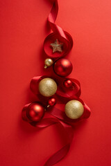 Vertical arrangement of red Christmas ornaments with gold accents and ribbon on a bold red...