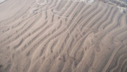 Moist sandy surface featuring patterns formed by ocean tides. Artistic nature backdrop. Premium photograph
