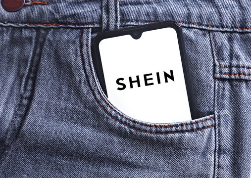 Shein logo on smartphone screen in jeans pocket. Shein logo online marketplace ecommerce on a smartphone