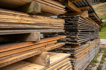Fototapeta premium Stacks of wooden planks and boards stored at lumber warehouse for construction and carpentry use