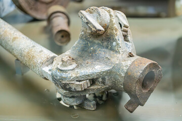 Rusted metallic object, possibly machinery part Indoor setting with other mechanical elements Corroded surface, soft shadows, diffused lighting Realistic style, close-up perspective No people or