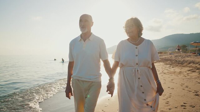 Happy senior couple walking hand in hand along the seashore at sunset, the woman showing the man a beautiful seashell she found, enjoying their retirement and creating romantic memories together