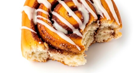 A close up of a partially eaten cinnamon roll with white icing on a white surface in bright lighting