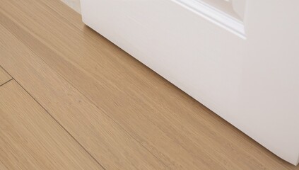 Close-up shot showcasing freshly laid wooden floor near a white door frame with a light, natural finish