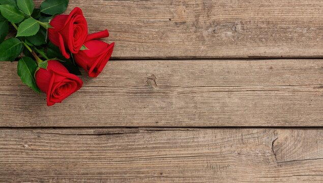 Fresh red roses arranged on a rustic wooden surface. Theme for romantic and natural floral design.