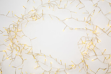 Warm fairy lights glowing on neutral background. Cozy hygge concept with copy space.