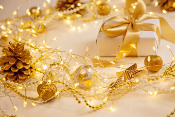 Christmas and New Year golden pinecone background with glowing garland and pearls. Cozy festive composition with copy space for text or design.