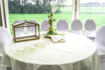 Eine Nahaufnahme eines Gästebuchs auf einem weißen Festtisch, festlich dekoriert für eine goldene Hochzeit. Das helle Buch mit dem Titel "Unsere Goldene Hochzeit" liegt mit einer goldenen Schleife und