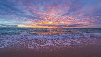 Obraz premium Nature's splendor unfolds with waves striking the shore, as a vivid sunset colors the horizon in stunning shades, crafting an unforgettable spectacle.