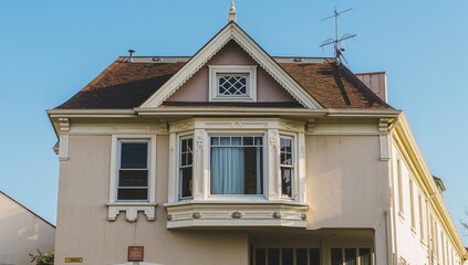 Light beige stucco exterior with a dark brown roof and white-trimmed windows under bright sunlight.