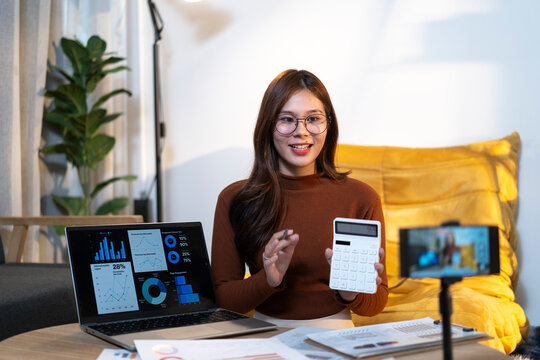 Woman vlogging financial planning using calculator and laptop