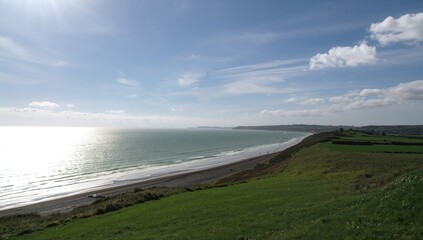 Gazing over the ocean from a coastal cliff with beach and natural scenery in summer light