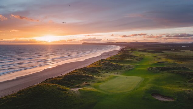 Aerial view of a coastal golf course at sunset - Powered by Adobe