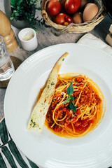 A delicious plate of spaghetti bolognese, beautifully presented with a breadstick