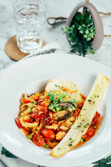 Delicious seafood pasta in a beautifully presented dish, with a slice of bread and a glass of water, perfect for food and culinary-themed visuals.