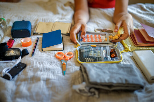 First aid kit - women's hands collecting medicines and emergency kit items