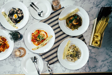 Delicious Italian pasta dishes artfully arranged on a table, with various ingredients, appealing colors, and artistic presentation, a culinary delight.
