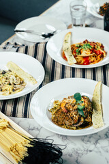 Deliciously plated pasta dishes ready to be savored, perfect for a culinary experience. The dishes are accompanied by a bread stick