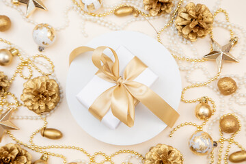 Golden Christmas and New Year frame with gifts, ornaments, pine cones, and pearls. Flat lay background with copy space for text or festive design.