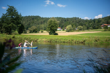 Mother paddleboarding with her children on a calm river, enjoying a peaceful outdoor adventure together