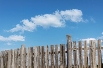Weathered wooden barrier under a bright azure sky