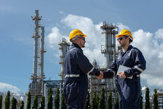Industrial engineers shaking hands at oil refinery plant, symbolizing teamwork, safety and partnership in petroleum production. construction worker oil plant.