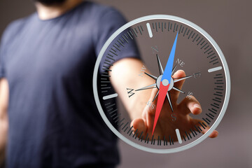Close-up of a man's hand holding a compass, representing direction, navigation, guidance, and...